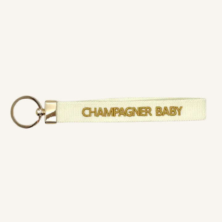 Portachiavi in tessuto intrecciato bianco con scritta ricamata oro "CHAMPAGNER BABY"